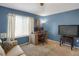 Bedroom featuring blue walls, neutral carpet, a large window, a desk area, and a TV on a small console table at 6476 Silver Mesa Dr # A, Highlands Ranch, CO 80130