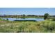 Scenic view of a tranquil pond surrounded by lush greenery and buildings on the horizon at 16860 Askins Loop # 102, Parker, CO 80134