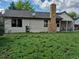 Home backyard featuring a large yard, brick chimney, and covered patio area at 16094 E Exposition Dr, Aurora, CO 80017