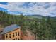 View of the rear side of a two-story home nestled among lush trees with an ascending dirt driveway at 15175 Rainbow Dr, Sedalia, CO 80135