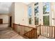 Upper hallway with a wood railing, wood floor, neutral walls and large windows offering a scenic view at 15175 Rainbow Dr, Sedalia, CO 80135