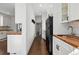 Open kitchen with white cabinets, butcher block countertops, stainless steel sink, and black refrigerator at 1612 S Logan St, Denver, CO 80210