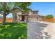 Charming two-story home featuring a well-manicured lawn and a three car garage on a sunny day at 12814 Forest Cir, Thornton, CO 80241