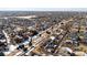 An aerial view of a community featuring diverse homes, tree-lined streets, and open spaces in a snowy landscape at 9140 E 29Th Ave, Denver, CO 80238