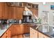 Kitchen featuring wooden cabinets, black countertops, tiled backsplash and stainless steel appliances and hood at 9140 E 29Th Ave, Denver, CO 80238