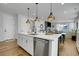 Open-concept kitchen with a stainless steel dishwasher, quartz countertop, and stylish pendant lighting at 4040 Eaton Park St, Aurora, CO 80019
