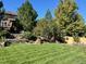 Lush backyard with manicured lawn, mature trees, and a charming garden at 3188 Lynwood Ave, Highlands Ranch, CO 80126