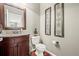 Stylish half bathroom with cherry vanity, framed mirror, and decorative wall art at 3188 Lynwood Ave, Highlands Ranch, CO 80126