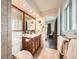 This bathroom includes a dark wood vanity with large mirror, tile floors, and a view into the Primary bedroom at 1977 S Urban St, Lakewood, CO 80228