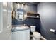 Stylish powder bath with blue walls, shelving and round mirror at 11376 Forest Dr, Thornton, CO 80233