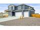 Two-story home featuring a three-car garage, wood siding, and rocky front yard at 562 Twilight Ct, Fort Lupton, CO 80621