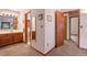 Hallway view leads to bathroom with wood cabinets, featuring mirrors, adjacent toilet room, and neutral color scheme at 34480 Pine Ridge Cir, Elizabeth, CO 80107