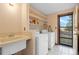 Bright laundry area with sink, white appliances, tile floors, and a backyard view at 34480 Pine Ridge Cir, Elizabeth, CO 80107