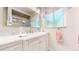 Bright bathroom featuring a sink, marble countertop, framed mirror, and framed window at 11542 W 29Th Pl, Lakewood, CO 80215
