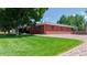 Well-maintained red brick house featuring lush green lawn and landscaped perimeter at 11542 W 29Th Pl, Lakewood, CO 80215