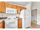 Clean kitchen featuring white appliances and wood cabinets with laundry room in the background at 3261 S Waco Ct # C, Aurora, CO 80013