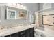 Bathroom featuring granite countertop, dual sinks, framed mirror, and tiled shower with bathtub at 7262 Serena Dr, Castle Pines, CO 80108