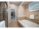The bathroom has a bathtub with tile surround and a glass door shower, and a peek into the walk-in closet at 23951 E Easter Pl, Aurora, CO 80016
