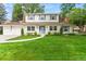 Charming two-story home featuring a lush green lawn, blue door, and lovely landscaping at 5061 S Florence Dr, Englewood, CO 80111