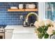 Bright kitchen with stainless appliances, quartz countertop, floating shelves, and blue backsplash at 5061 S Florence Dr, Englewood, CO 80111