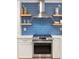 Modern kitchen with stainless steel range, blue subway tile backsplash and floating wood shelves at 5061 S Florence Dr, Englewood, CO 80111