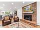 Living room featuring a brick fireplace with wooden mantel and hearth, flanked by matching leather armchairs at 5061 S Florence Dr, Englewood, CO 80111