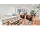 Bright living room with hardwood floors, neutral sofa, and open access to a modern kitchen with island seating at 5061 S Florence Dr, Englewood, CO 80111