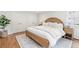 Comfortable main bedroom with wicker bed frame, white bedding, and hardwood floors at 5061 S Florence Dr, Englewood, CO 80111