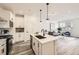 Open-concept kitchen featuring white cabinets, a center island with bar seating, and modern pendant lights at 348 N. Geneva St, Aurora, CO 80010