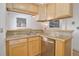 Compact kitchen featuring stainless steel dishwasher, blonde wood cabinets, and light countertops at 1629 N Clarkson St # 13, Denver, CO 80218