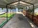 Metal carport covering a long driveway with grass and fence at 1738 Dallas St, Aurora, CO 80010