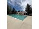 A sparkling community swimming pool surrounded by concrete and lush landscaping on a sunny day at 921 S Walden Street # 205, Aurora, CO 80017