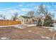 Charming single-story home featuring a gravel driveway, a new fence, a green roof, and mature landscaping at 6900 E 66Th Ave, Commerce City, CO 80022