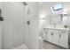 Modern bathroom with a walk-in shower, white vanity, and skylight at 1155 Garfield St, Denver, CO 80206