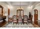 Elegant dining room with hardwood floors, designer rug, chandelier, arched entry, and seating for eight at 1042 Country Club Estates Dr, Castle Rock, CO 80108