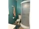 Compact blue bathroom featuring a glass-enclosed shower, toilet, sink, towel, and window with white blinds at 5618 Carr St, Arvada, CO 80002