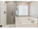 Bright bathroom featuring a glass shower with gray herringbone tile and a soaking tub beneath a window at 6364 Fulton St, Denver, CO 80238