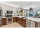 Open concept kitchen with stainless steel appliances, wooden cabinets, large island and adjacent living room at 6364 Fulton St, Denver, CO 80238