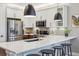 Modern kitchen boasts white countertops, stainless appliances, a breakfast bar, and dark pendant lighting at 6364 Fulton St, Denver, CO 80238