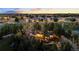 Gorgeous aerial view of a private home surrounded by mature trees with beautifully lit exterior lights at twilight at 1 Greenridge Rd, Greenwood Village, CO 80111