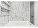 Bathroom with marble-look wall tiles, gray accent tile, and built-in shelves at 5995 W Hampden Ave # 5I, Denver, CO 80227