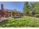 Manicured backyard featuring a covered patio, seating, lawn, and privacy fence at 2093 S Holland St, Lakewood, CO 80227