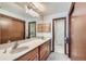 Bathroom with double sinks, wood cabinets, large mirror, and a separate toilet room at 2093 S Holland St, Lakewood, CO 80227