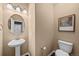 Small powder room featuring a pedestal sink, a round mirror, modern lighting, and a toilet at 2575 Mccracken Ln, Castle Rock, CO 80104