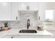 Modern kitchen details including stainless steel sink, fixtures, backsplash, and white cabinetry at 855 Newark St, Aurora, CO 80010