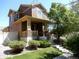 Inviting two-story home with a well-manicured lawn and landscaping, featuring a charming front porch at 7354 Benton St, Arvada, CO 80003