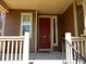 A cozy front porch featuring a vibrant red door, complemented by stylish railings and welcoming details at 7354 Benton St, Arvada, CO 80003