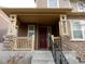 Close-up of a home's inviting front porch with stone pillars and a dark red door at 7354 Benton St, Arvada, CO 80003