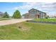 Two-story home featuring a well-maintained lawn, three-car garage, and a large tree in the front yard at 16500 Timber Cove St, Hudson, CO 80642