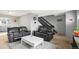 Cozy living area featuring black leather sofas, stairs, and neutral decor at 6838 S Broadway, Centennial, CO 80122